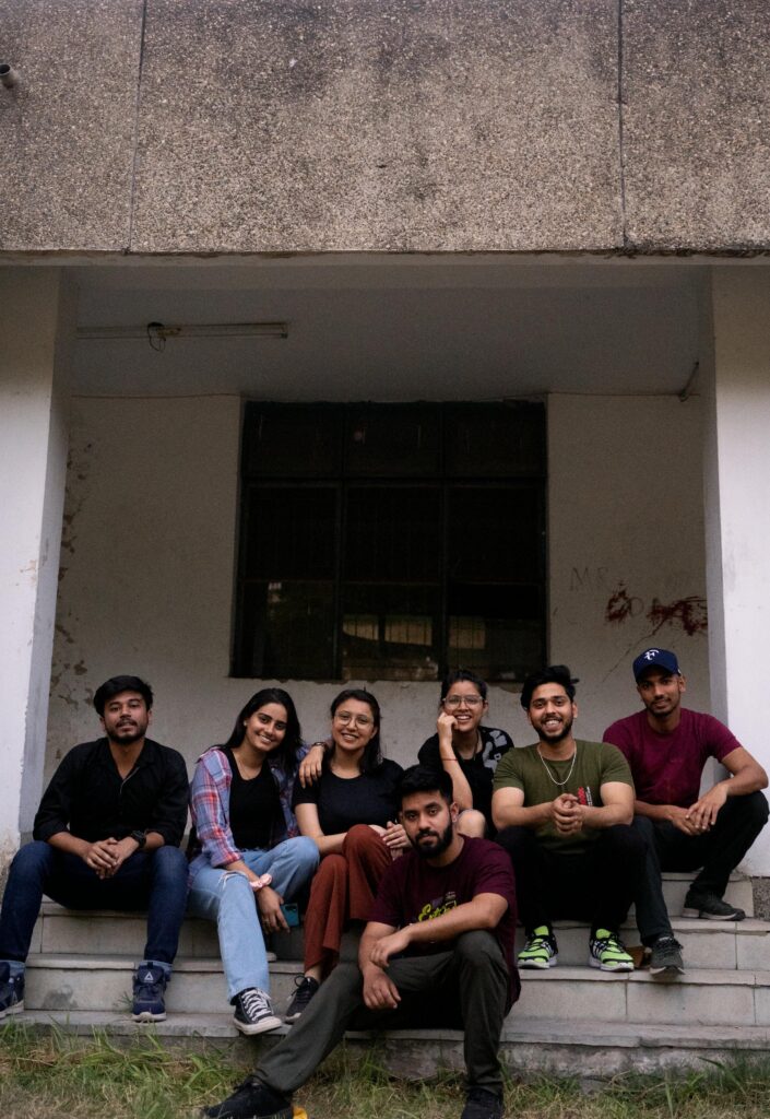 A group of friends smiling while sitting on outdoor steps, capturing a casual and joyful moment.